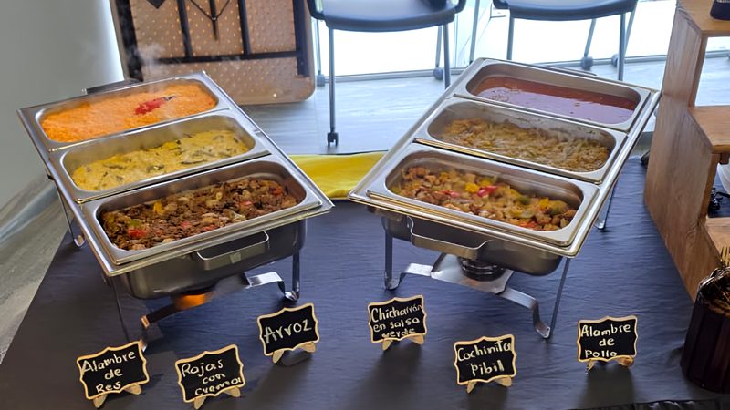 Taquiza montada tipo buffet con charolas y letreros de guisados