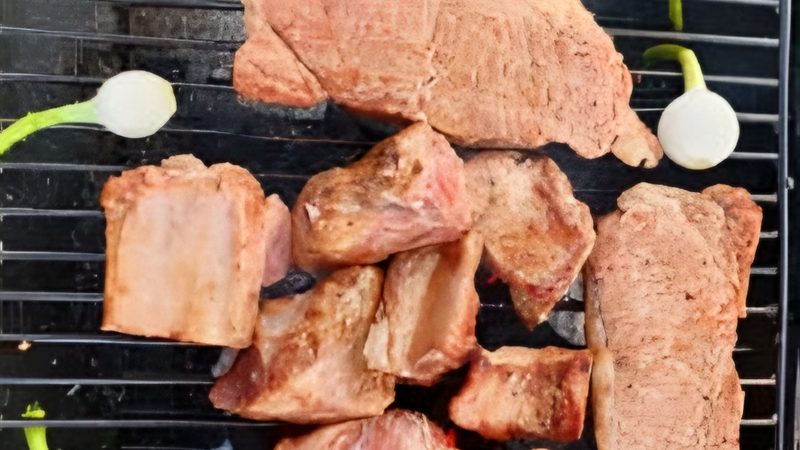Cortes de carne y cebollitas en la parrilla